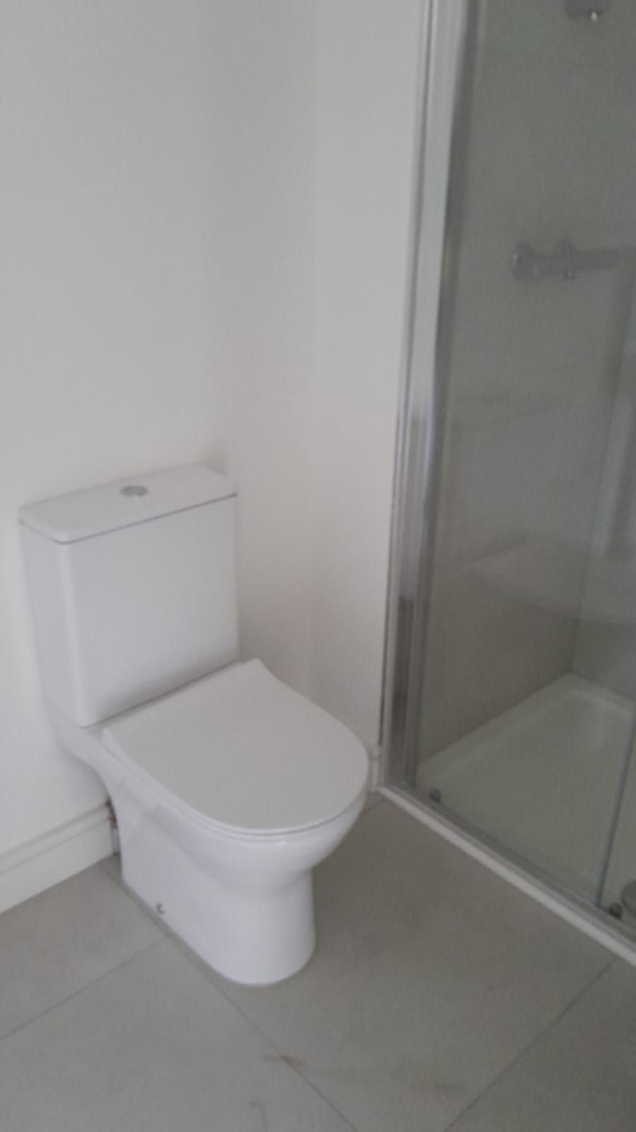 Toilet installed beside a shower in a refitted bathroom