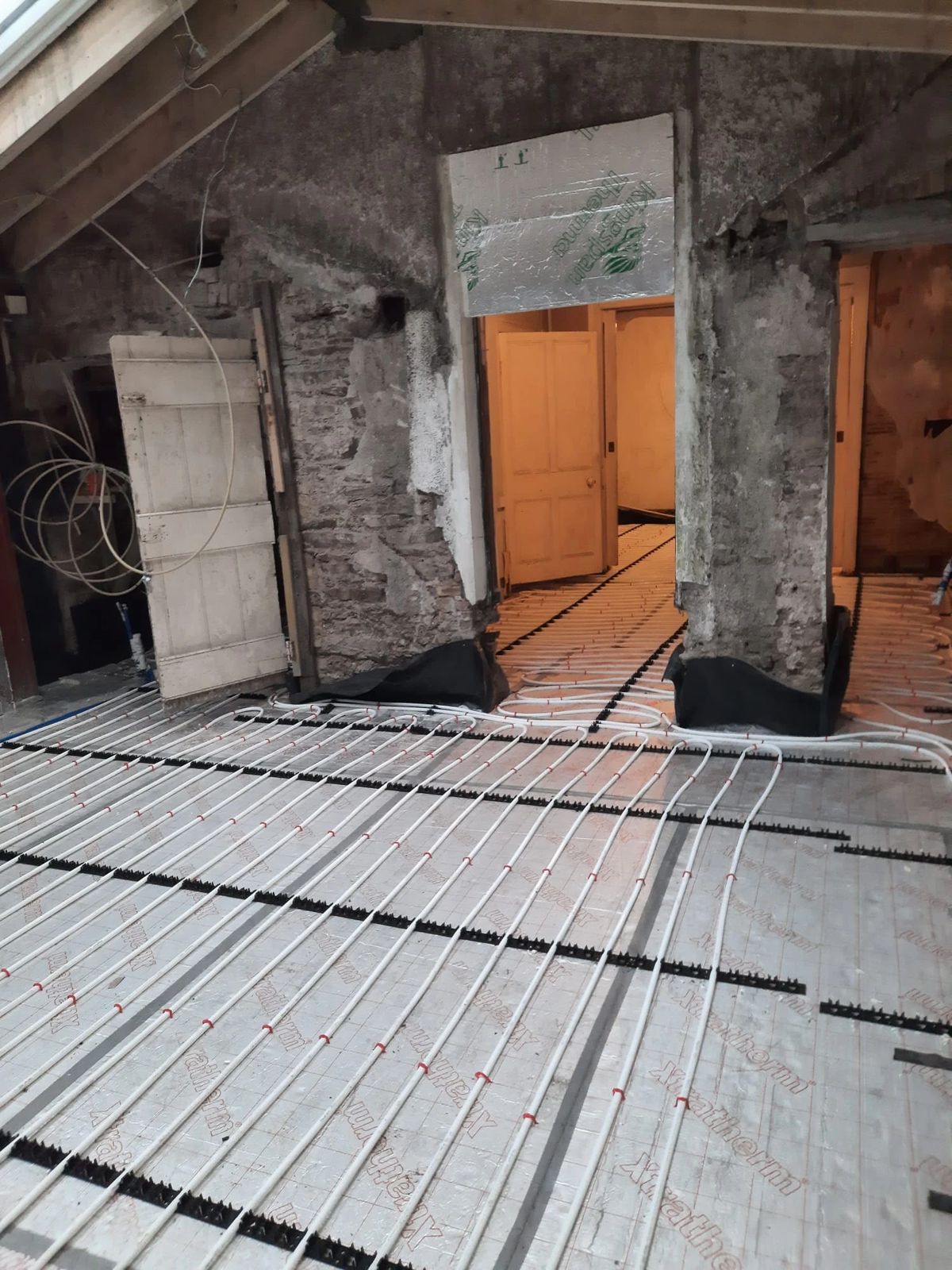 Underfloor heating pipes laid in an old house under exposed joists