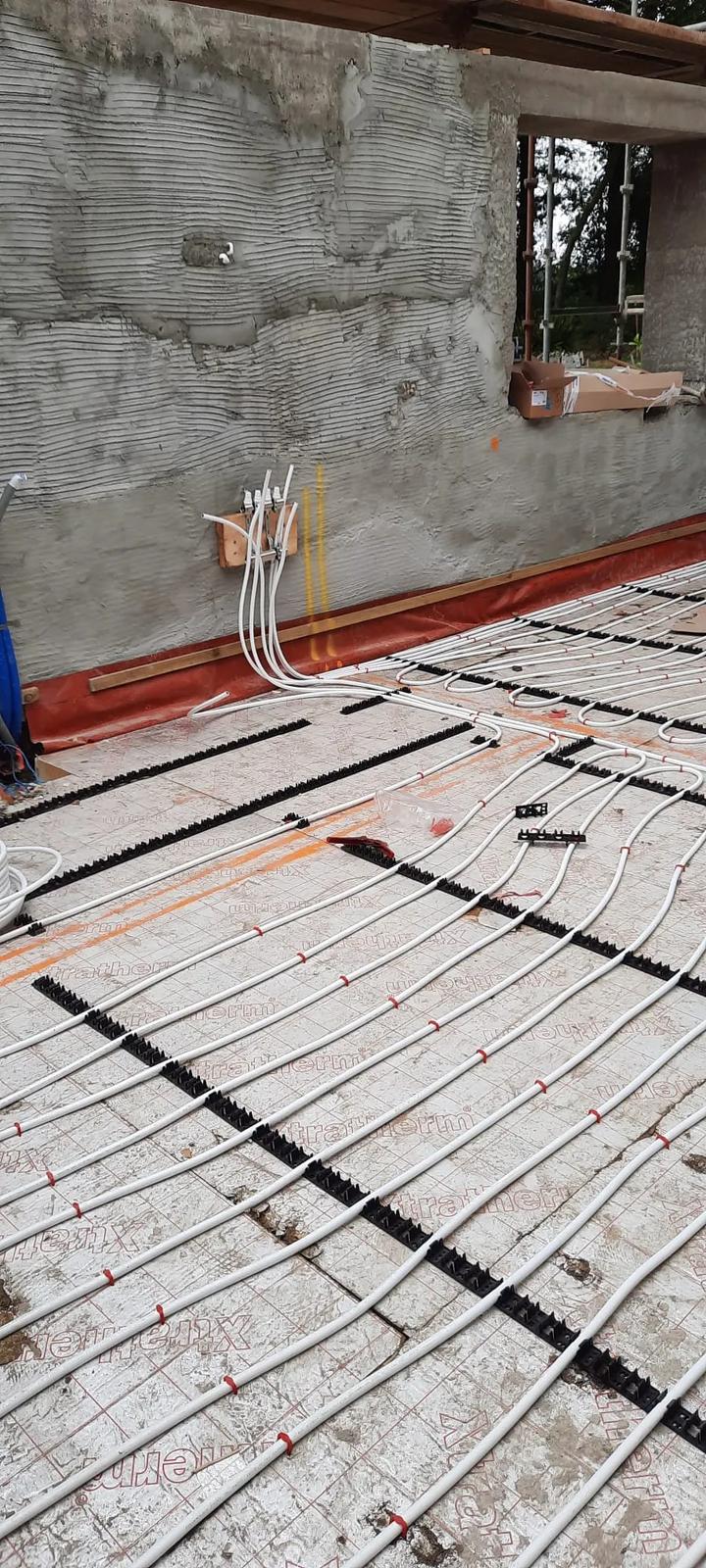 Underfloor heating pipes running to the manifold at a rendered wall